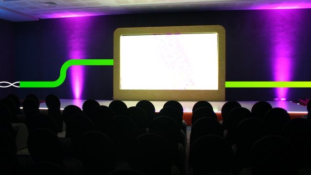 Escenario preparado para lanzamiento de producto en evento corporativo con iluminación y pantalla central